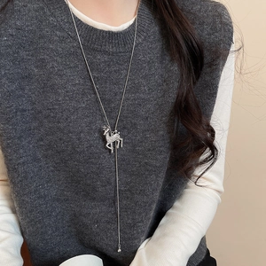 Close-up of silver reindeer pendant necklace with white diamonds on a grey sweater