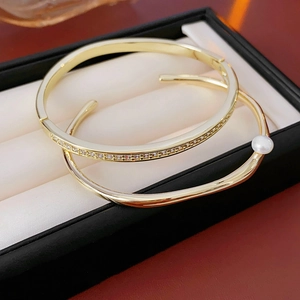 Detail of gold geometric bracelets with pearls and zircons in a black jewelry box
