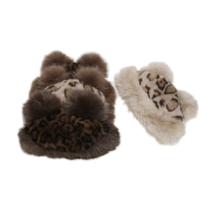 Detail view of winter faux fur ear covers with leopard print and plush pom-pom accents