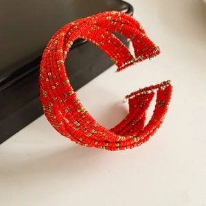 Détail du bracelet multicouche en perles de verre rouge et or avec motif ethnique tissé