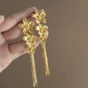 Detail of gold floral tassel earrings featuring multi-layered flower petals and long chains