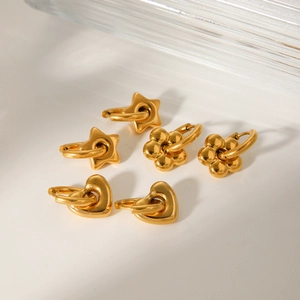 Macro view of gold heart and flower pendants on polished stainless steel hoops
