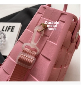 Detail of pink EVA bag featuring a gold metal hook and adjustable nylon shoulder strap