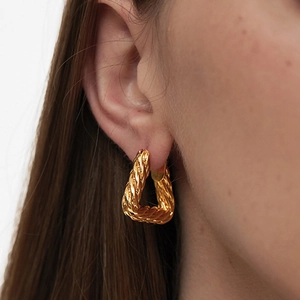 Textured 18K gold triangular hoop earrings for women shown on ear in a profile view