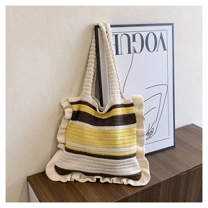 Detail of hand-woven striped tote bag with ruffle edges on a rustic wooden cabinet