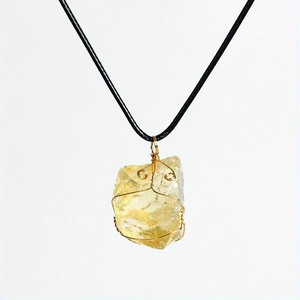 Detail of wire-wrapped natural citrine crystal pendant on black woven cord necklace