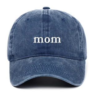 Detailed view of white 'mom' embroidery on dark blue washed cotton baseball cap