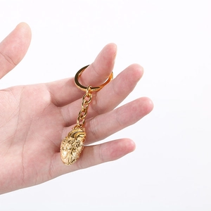 Detailed view of a golden anatomical heart keychain with intricate vascular textures