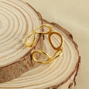 Detail of 18k gold open ring with teardrop pattern and hammer texture on wood base
