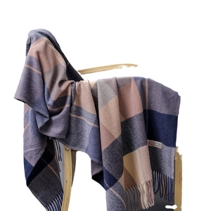 Plaid cashmere scarf in navy blue and beige with fringe on a wooden chair