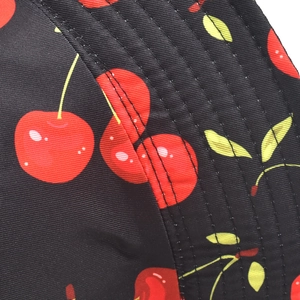 Gros plan détaillé du motif cerise sur tissu noir avec coutures du chapeau de soleil