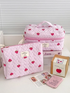 Detailed close-up of pink strawberry quilted makeup bag with striped texture and cotton handle