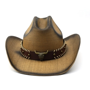 Detail of western straw cowboy hat featuring a bull skull ornament and leather band