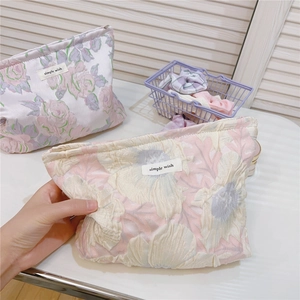 Detail of floral bubble jacquard fabric and simple wish label on pink cosmetic bag