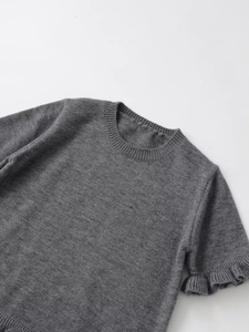 Detailed close-up of grey short-sleeve knit sweater featuring ruffled cuff craftsmanship