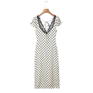 Close-up of V-neckline with black lace trim and polka dot pattern on white dress