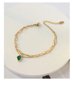 Detailed view of gold double-layer chain bracelet featuring a green geometric stone pendant