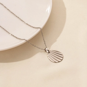 Macro shot of silver oval pendant with shell texture on thin stainless steel O-chain