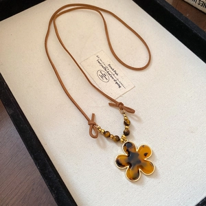 Macro view of flower pendant necklace featuring tiger eye stones and amber resin texture