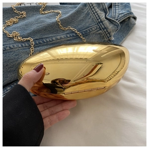 Close-up of gold mirror finish hard shell clutch bag with stylish metallic chain strap