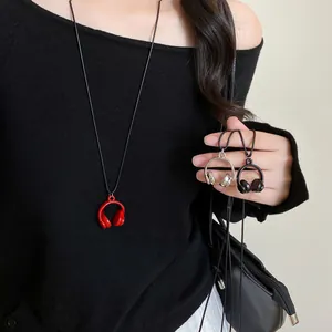Détail de pendentifs casque créatifs en rouge, noir et argent sur un collier à cordon