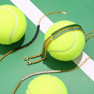 Detailed shot of gold-plated tennis bracelets with colorful zircons on a tennis ball