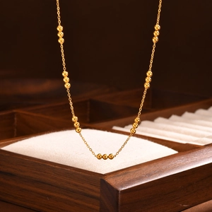 Elegant gold beaded stainless steel necklace displayed on a premium wooden box