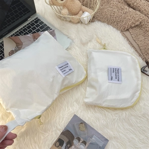 Detail of white waterproof travel organizers with yellow zippers on a soft plush background