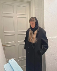 Close-up of a women's black wool coat with a matching knitted hooded balaclava scarf