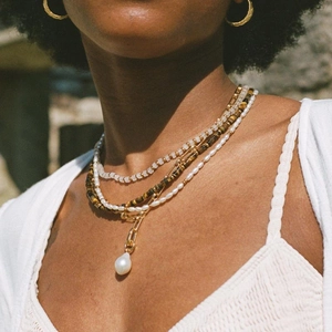 Close-up of layered bohemian necklace with baroque pearls, tiger eye beads and gold chains