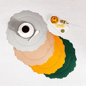 Detail of four stacked round faux leather placemats with vintage embossed patterns