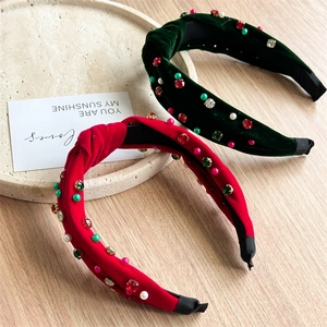 Gros plan de serre-têtes en velours rouge et vert avec strass et perles sur bois