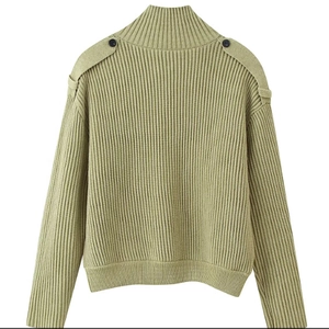 Detail of light green ribbed knit sweater with buttoned shoulder epaulettes and mock neck