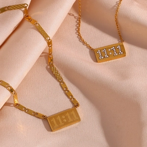 Macro detail of gold-plated 11:11 rectangular pendants with crystal and engraved designs