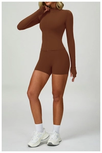 Detail of dark brown zip-up yoga top with thumbholes and matching high-waist sports shorts