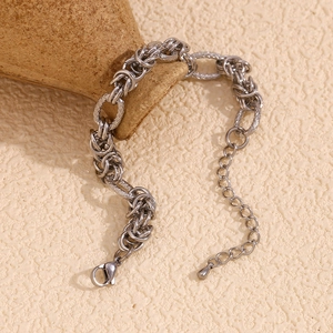 Detail of silver chain bracelet with lobster clasp on textured ceramic pottery