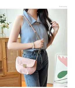 Détail du sac selle rose avec boucle coeur dorée et bandoulière chaîne sur modèle