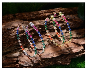 Macro shot of 14k gold and silver hoop earrings with multicolored teardrop zircons