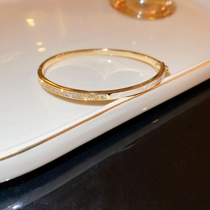 Dettaglio del bracciale dorato con pietre di zircone pavé e gemma centrale quadrata