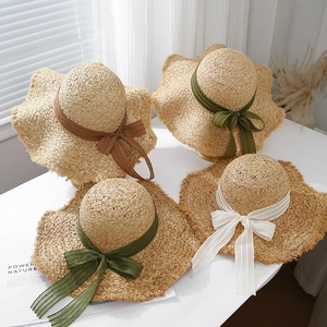 Detail of colorful raffia sun hats with wavy brims and elegant ribbon bow decorations