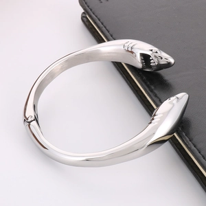 Macro detail of silver stainless steel cuff bracelet featuring dual shark head carvings