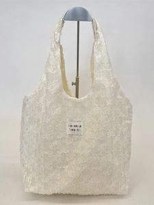 Off-white floral jacquard lace tote bag with brand label on a metal display stand