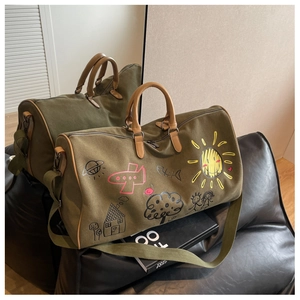 Detail of army green canvas travel bag with playful hand-drawn graffiti and leather handles