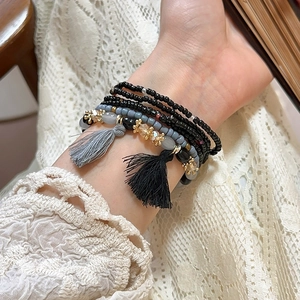 Detail of layered Bohemian beaded bracelet with gold accents and colorful silk tassels