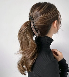 Detail view of a large leopard print banana hair clip worn by a model in a ponytail