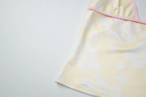Detailed close-up of yellow floral pattern and pink trim on a V-neck halter top