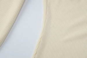 Detailed macro view of the cream-colored ribbed knit fabric texture and seam stitching