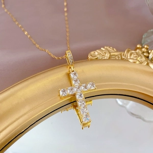 Detailed close-up of a golden titanium steel cross necklace set with sparkling zircons