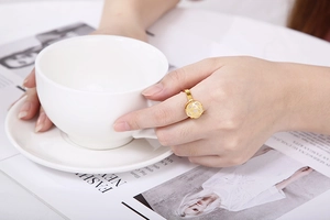 Detailed view of an elegant gold floral ring with pearl on a model hand with magazine