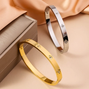 Detailed macro view of gold and silver starburst bangles with crystals on satin fabric